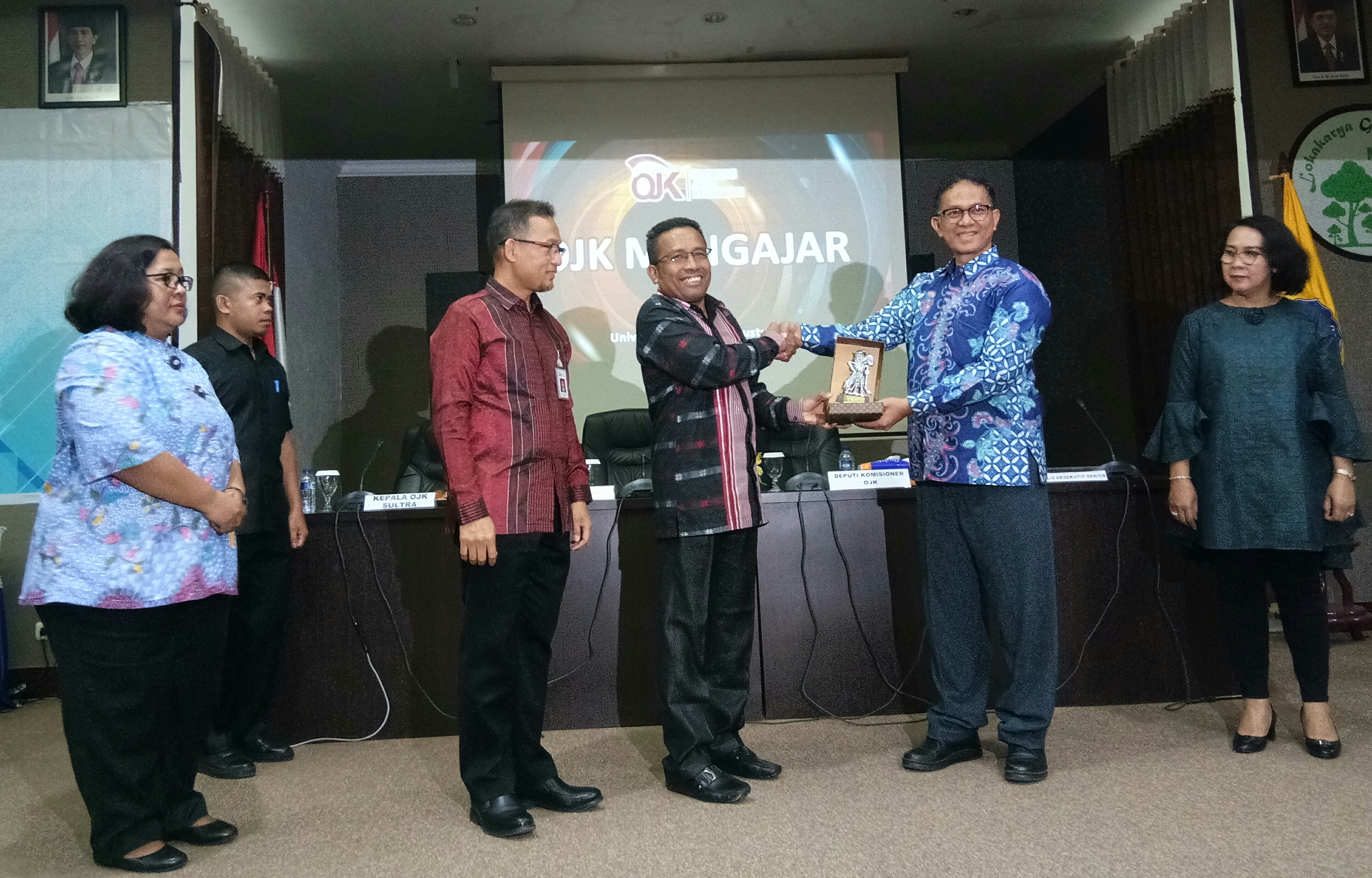 Deputy Komisioner OJK, Sukarela Batunanggar (kanan, batik biru) serahkan plakat kepada Rektor UHO Kendari, Muh. Zamrun. Foto: Ikas/TNC. 