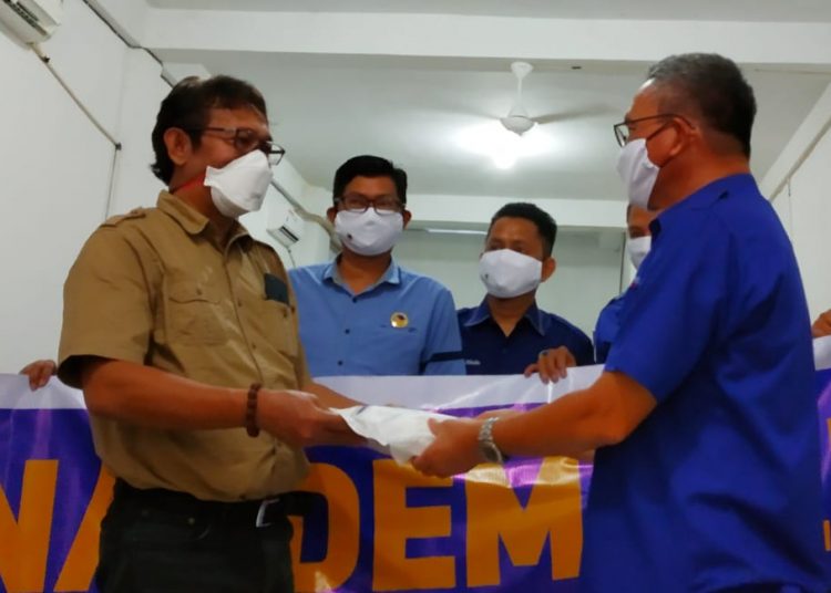 Ketua DPW NasDem Sultra, Tony Herbiansyah (kanan) serahkan bantuan APD kepada tenaga medis, yang diterima langsung oleh Ketua IDI Sultra, dr. Wayong (kiri). Foto: Ikas/TenggaraNews.com.