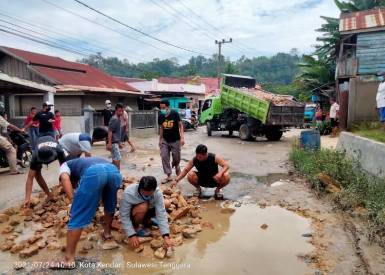 Aksan Jaya Putra membantu warga menimbun jalan yang rusak para di wilayah Kelurahan Kendari Caddi, Kota Kendari.