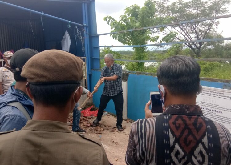 Haji Ismail Salam pakai kostum kotak-kotak membongkar pagarnya.